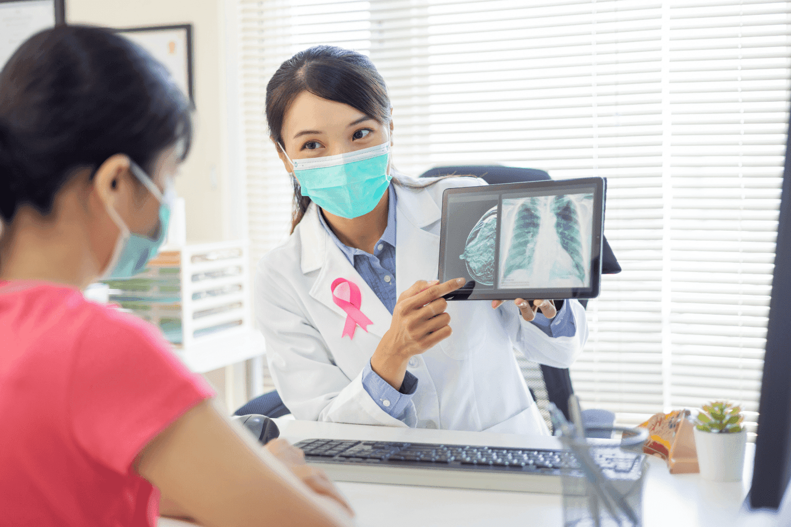 Female doctor wearing a mask showing a chest X-ray on a tablet to a patient.