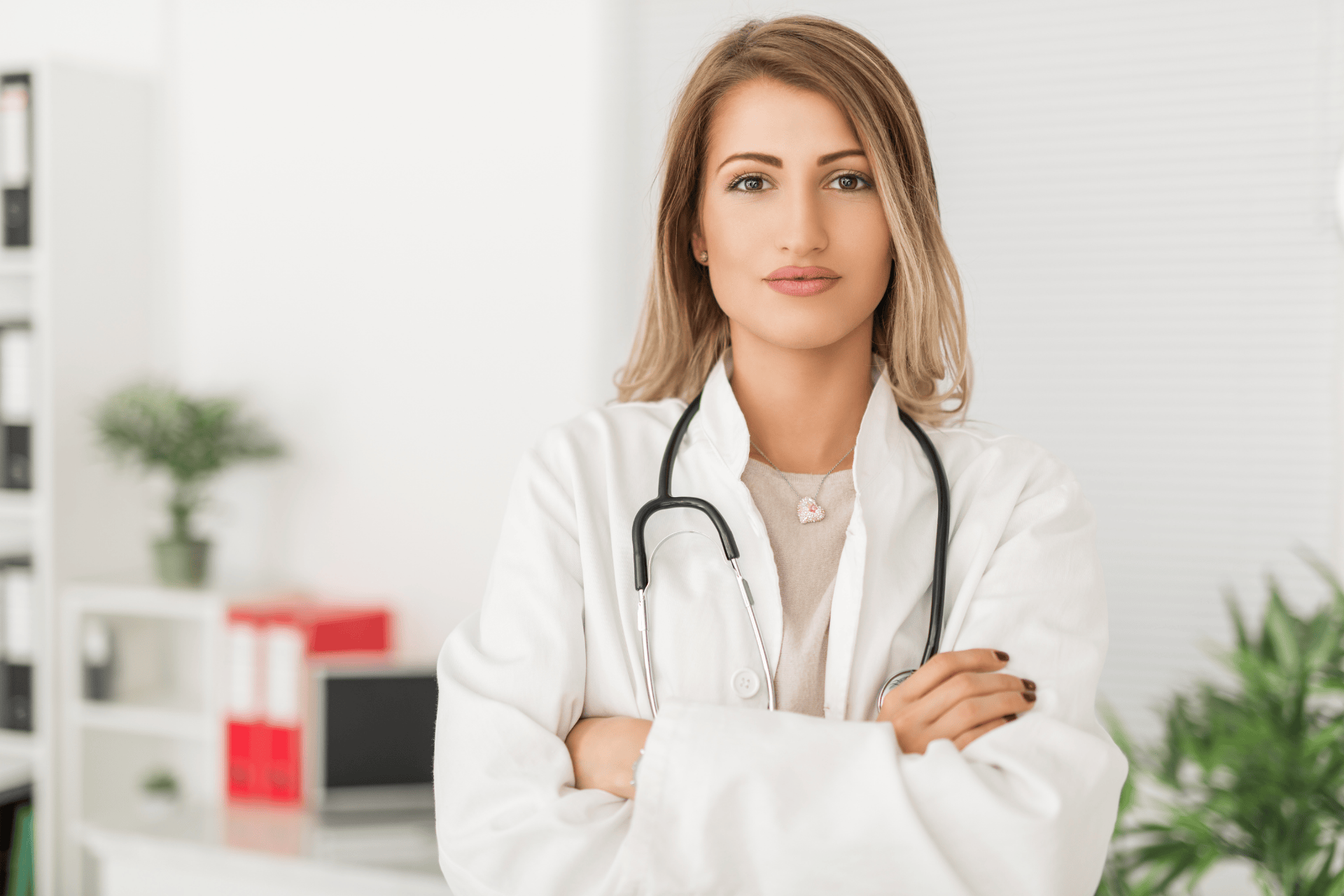 Female doctor with a stethoscope standing with arms crossed.