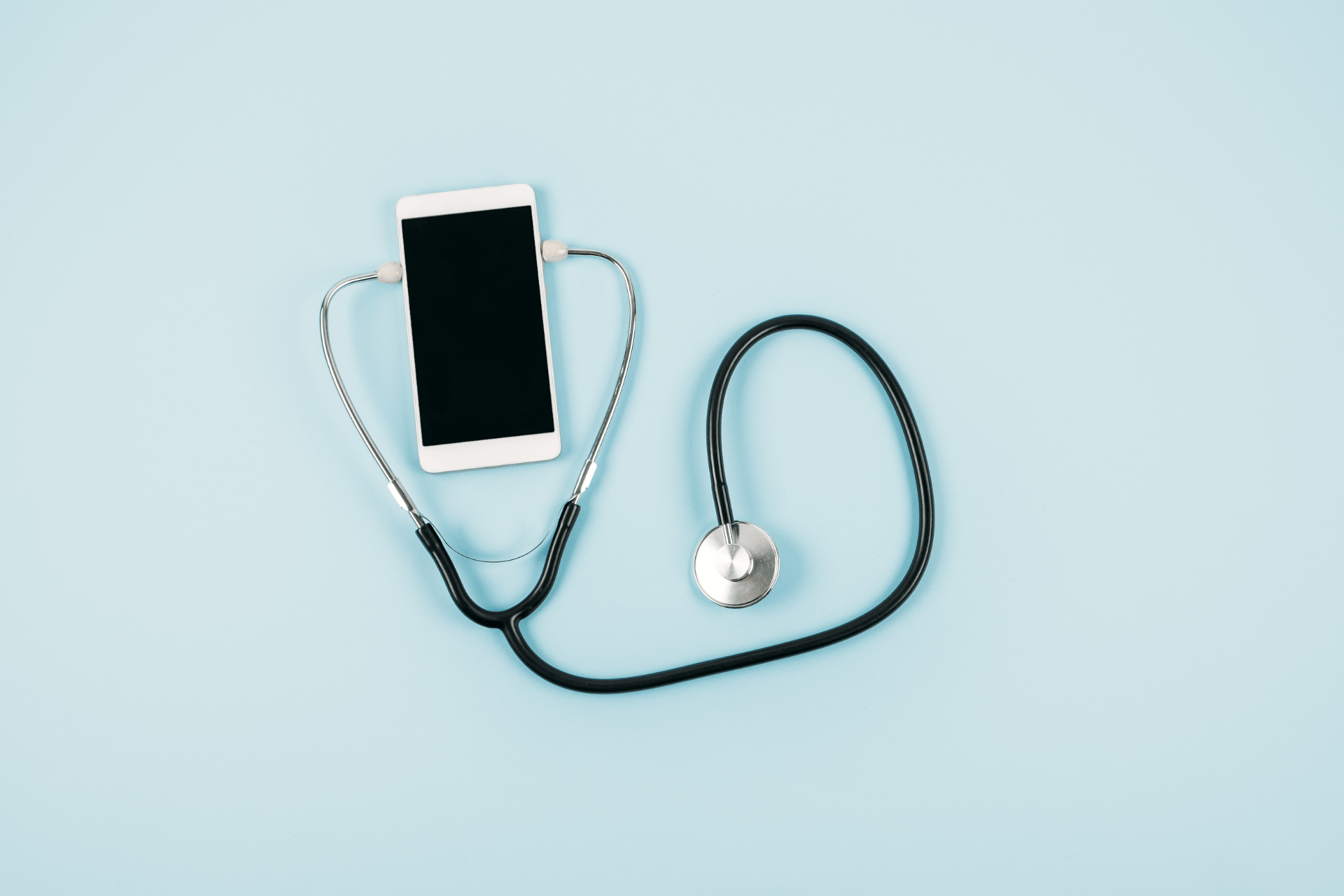 Stethoscope connected to a smartphone on a light blue background.