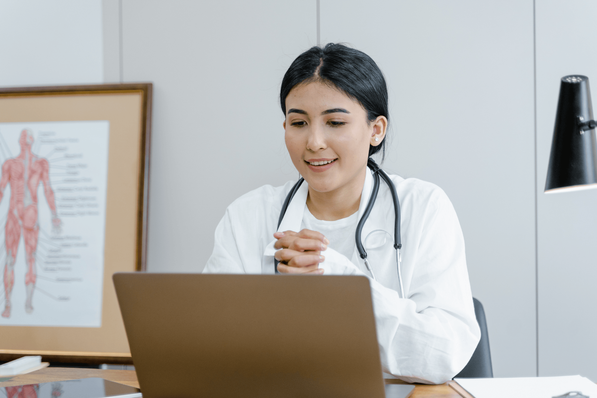 Doctor smiling while conducting an online consultation using a laptop.