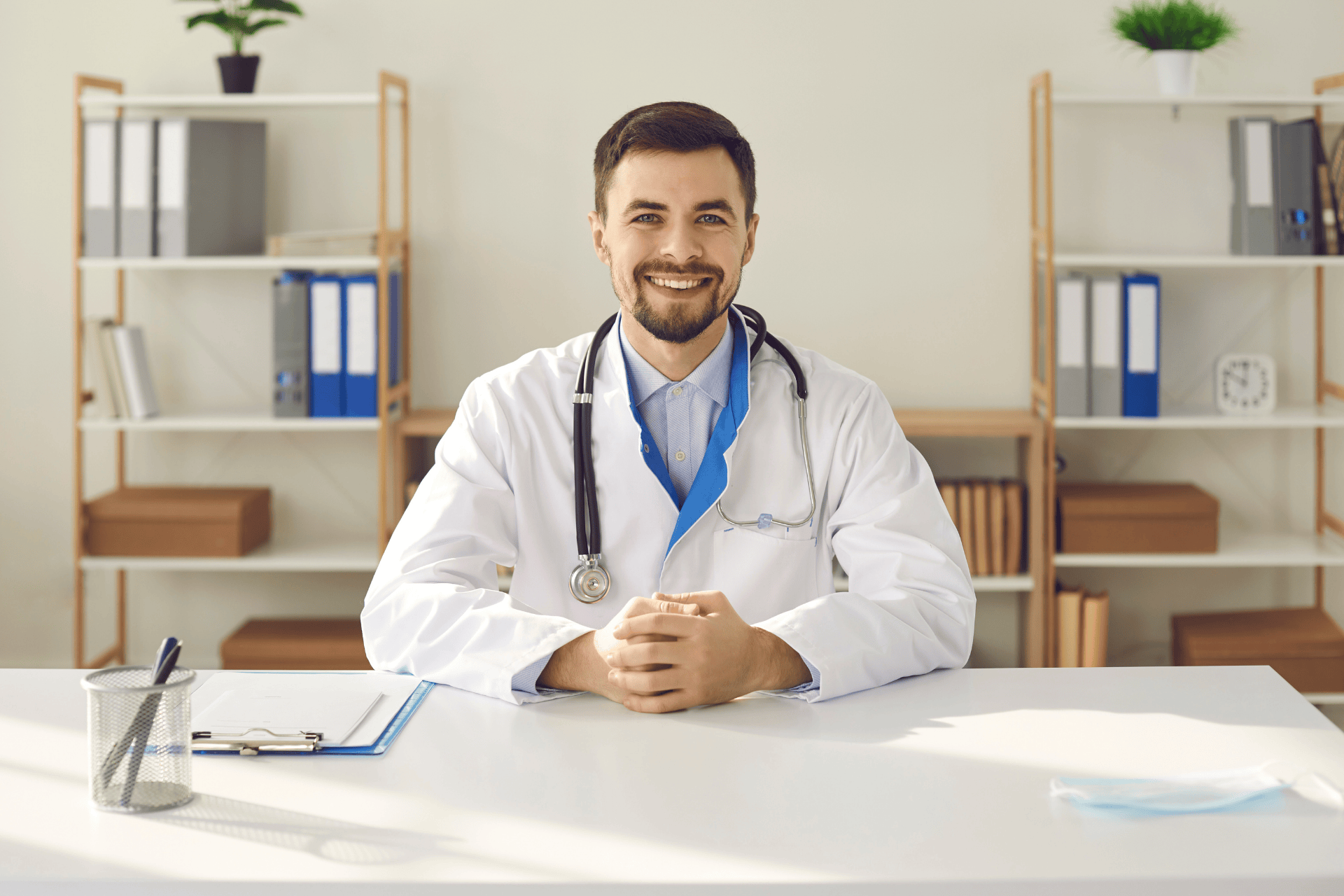 Smiling male doctor sitting at a desk in his office.