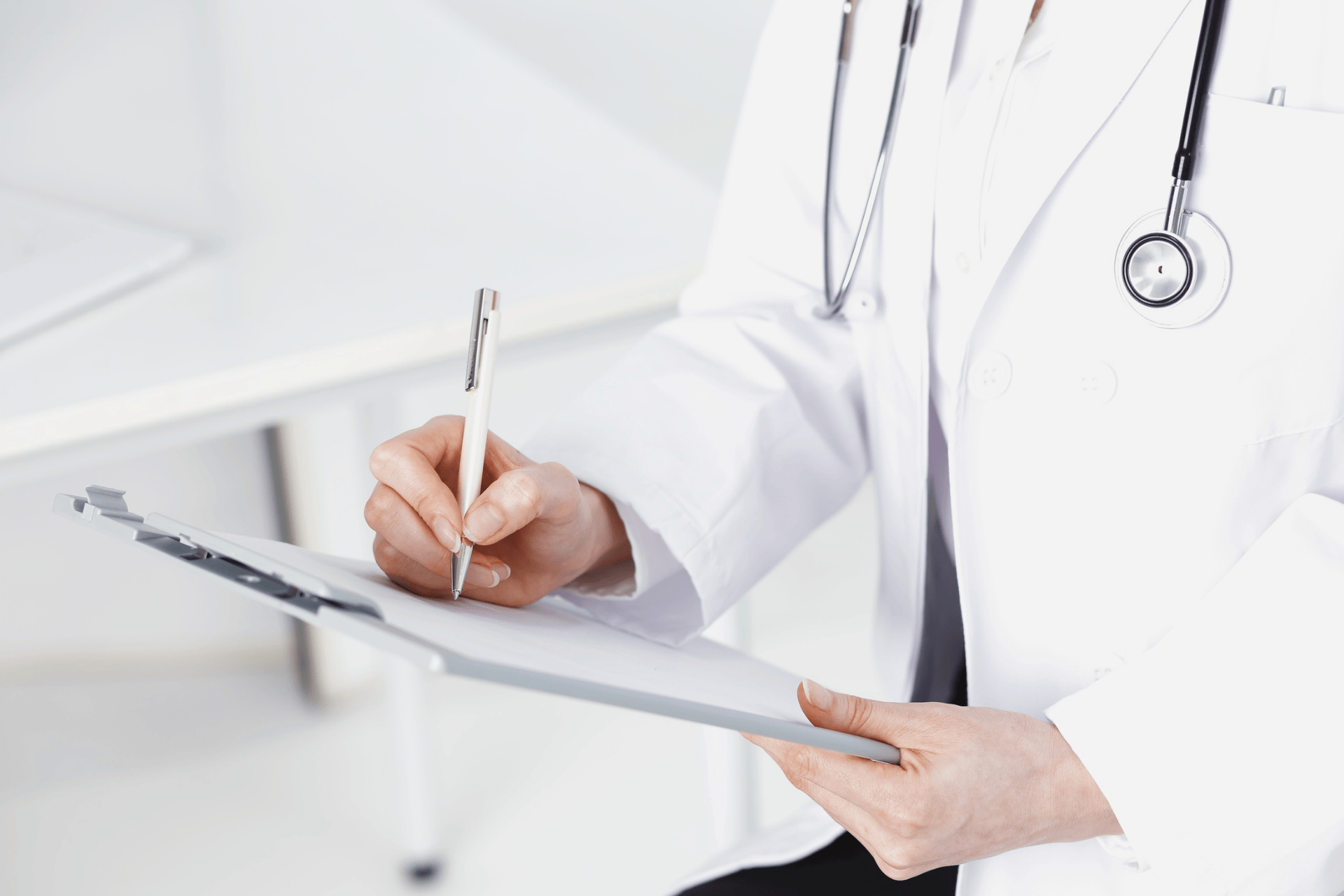 Doctor writing notes on a clipboard in a medical office.