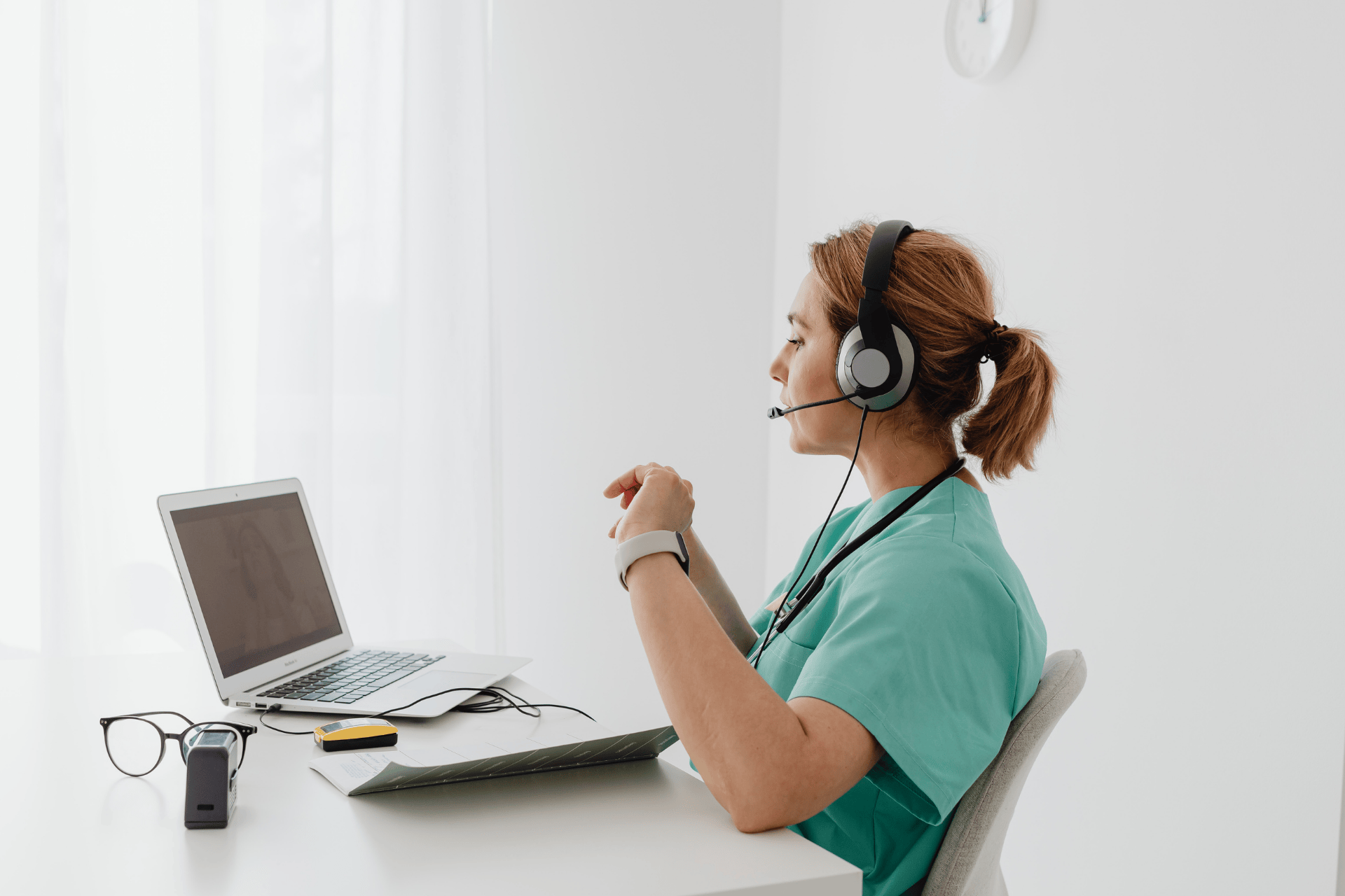 Nurse wearing a headset conducting an online consultation on a laptop.