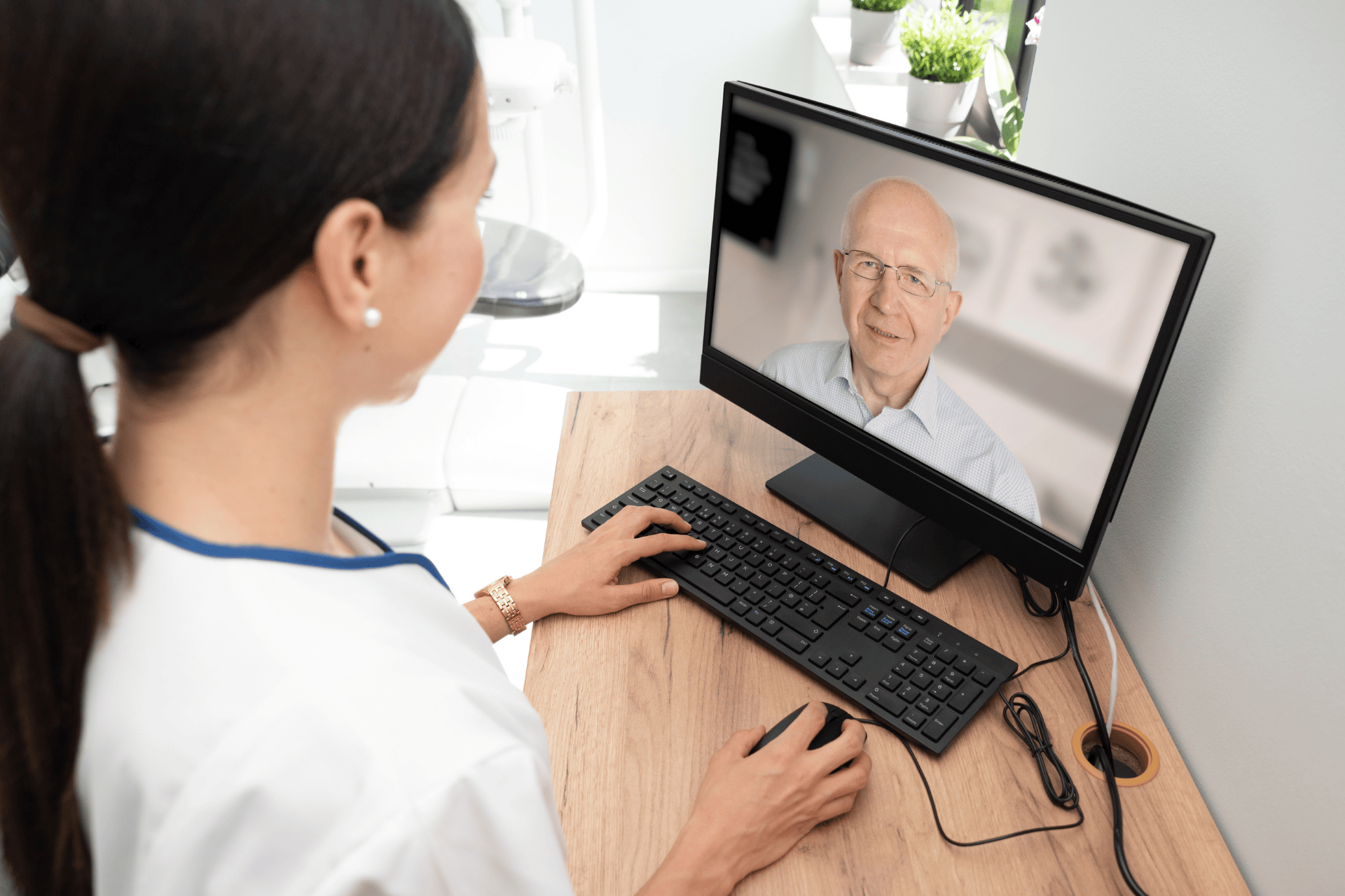 Woman having an online video consultation with an older man on a computer screen.