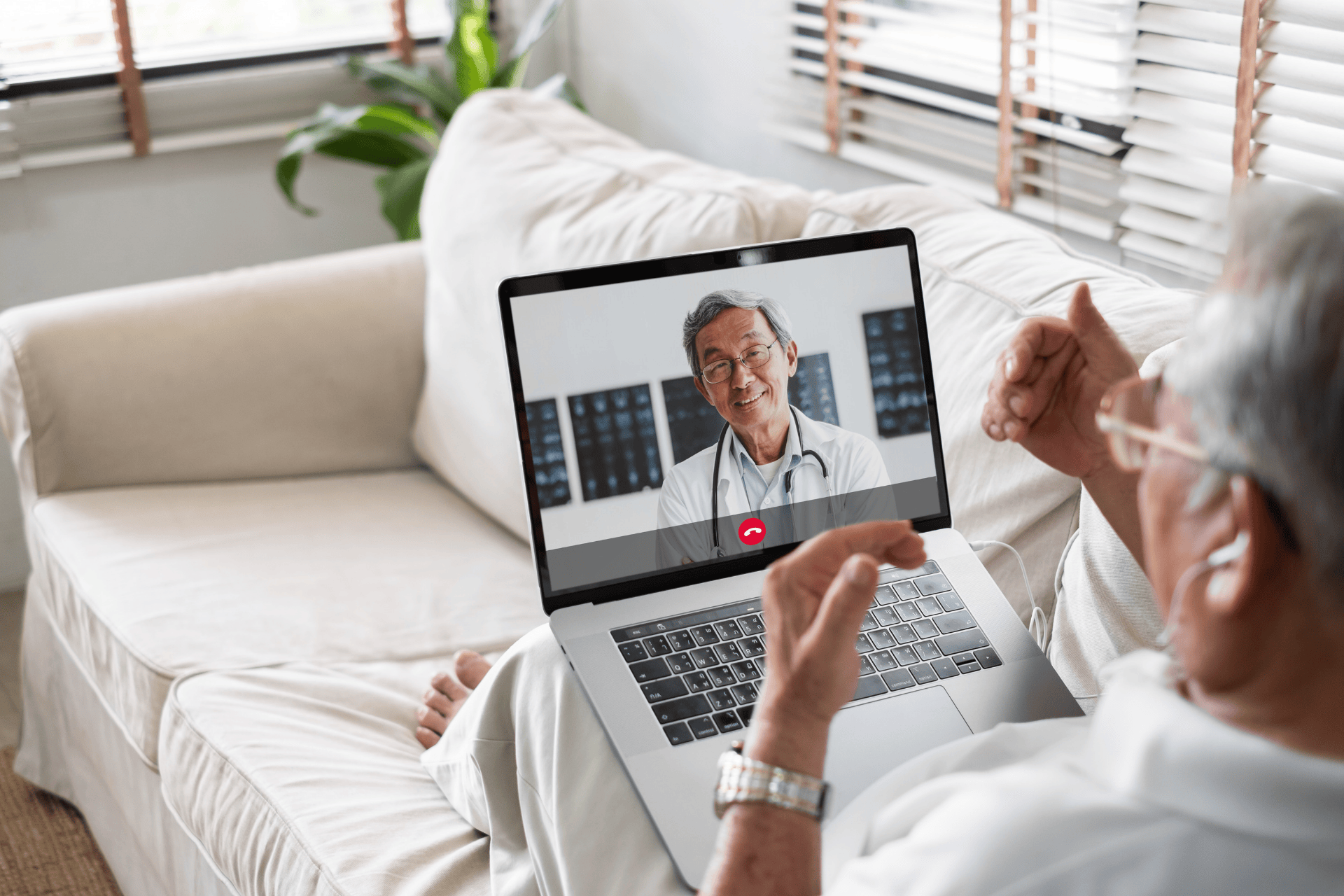 Older man having an online video call with a doctor on a laptop.