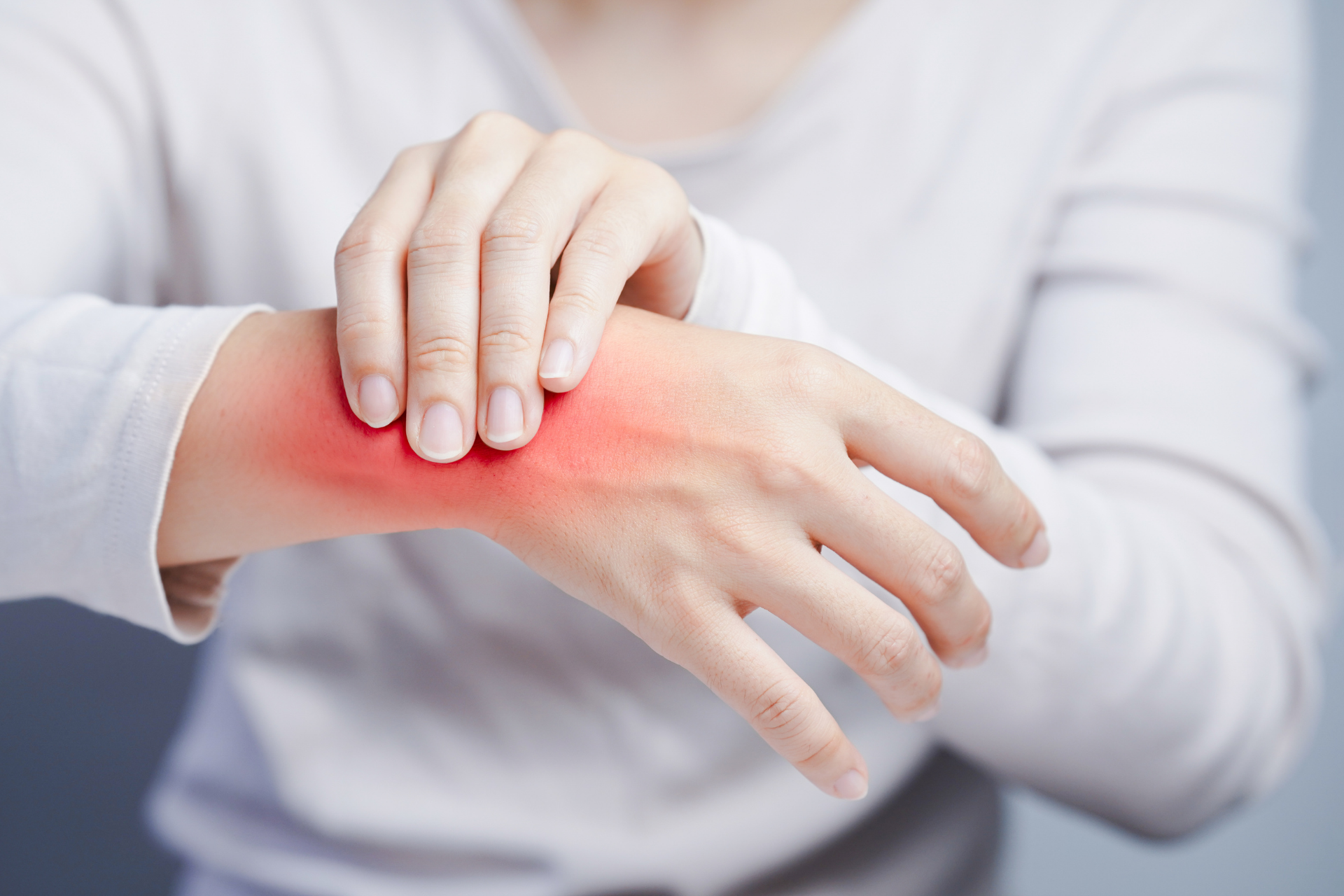 Person holding and touching a red, irritated area on their wrist