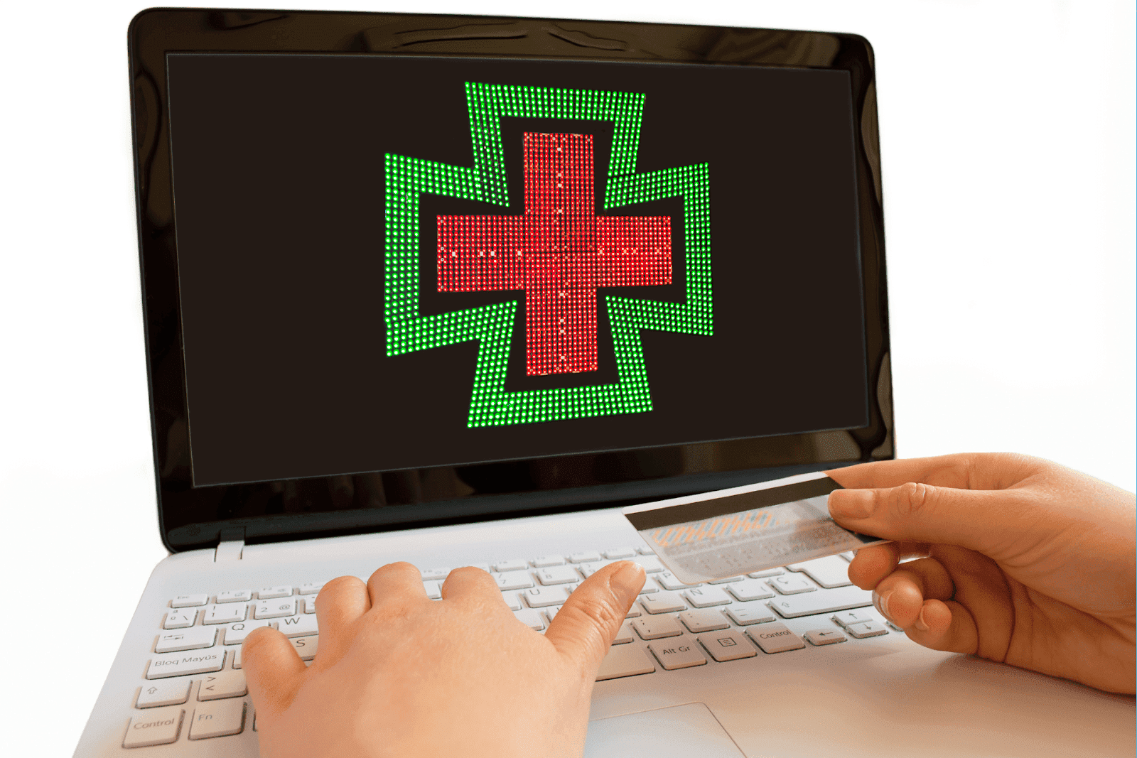 Hands holding a credit card while using a laptop with a green and red pharmacy cross on the screen