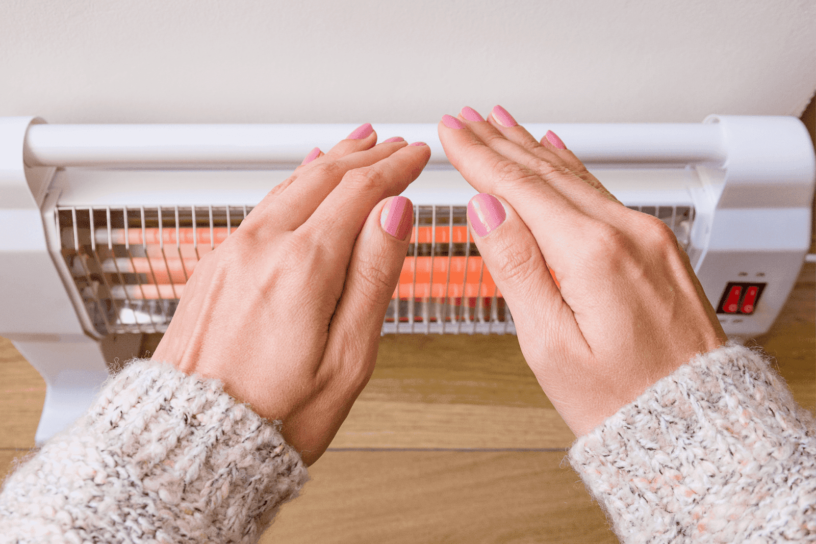 Hands warming in front of an electric heater.