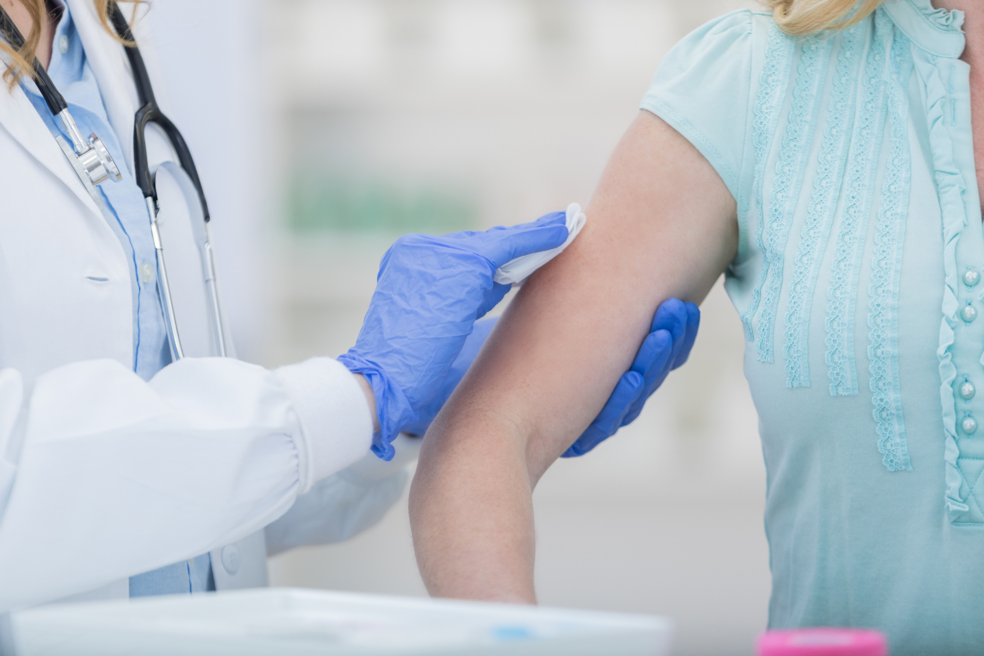 Healthcare provider wearing gloves prepares a patient’s arm for vaccination