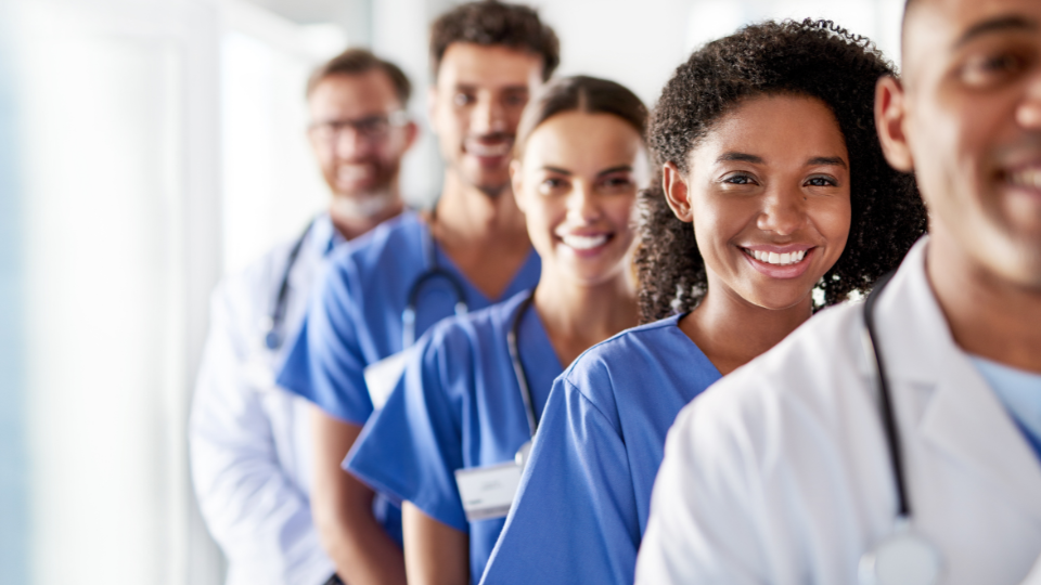 Medical professionals standing in a line smiling.