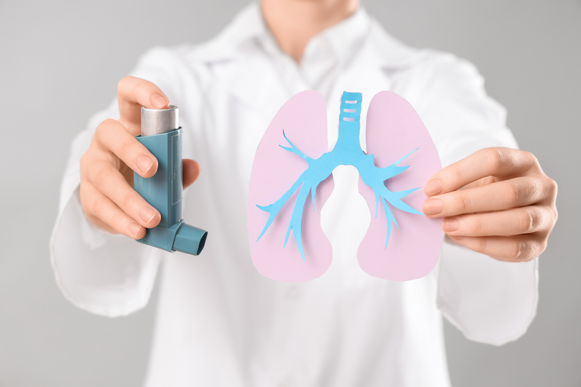 Healthcare professional holding an asthma inhaler and a paper cutout of lungs