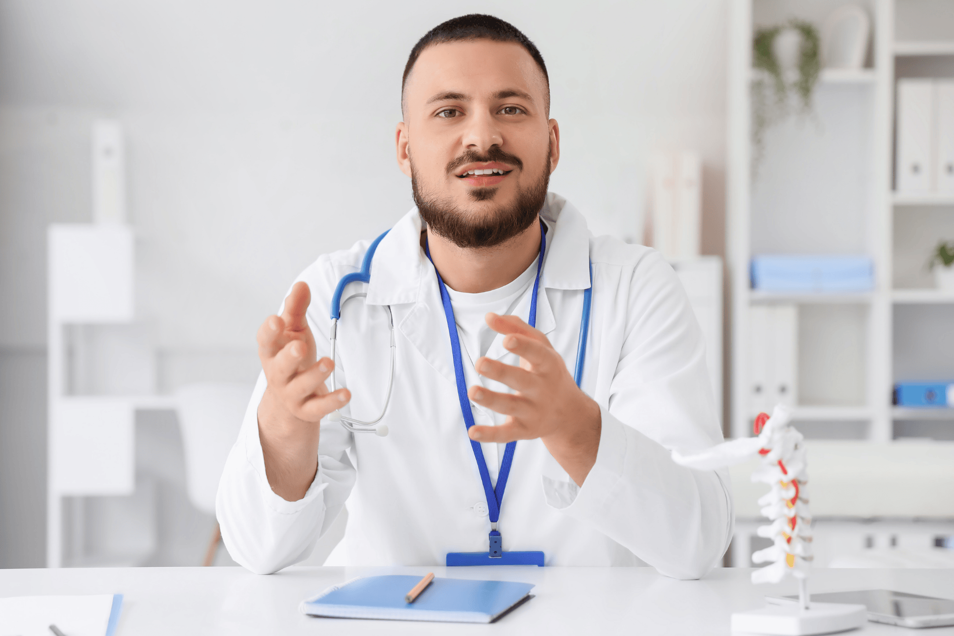Male doctor speaking with hands raised during a consultation.