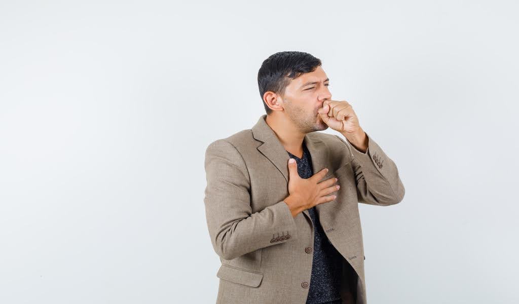 A man in visible discomfort, holding his chest tightly