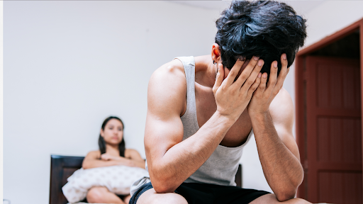 Man sitting in bed and covering his face with his hands