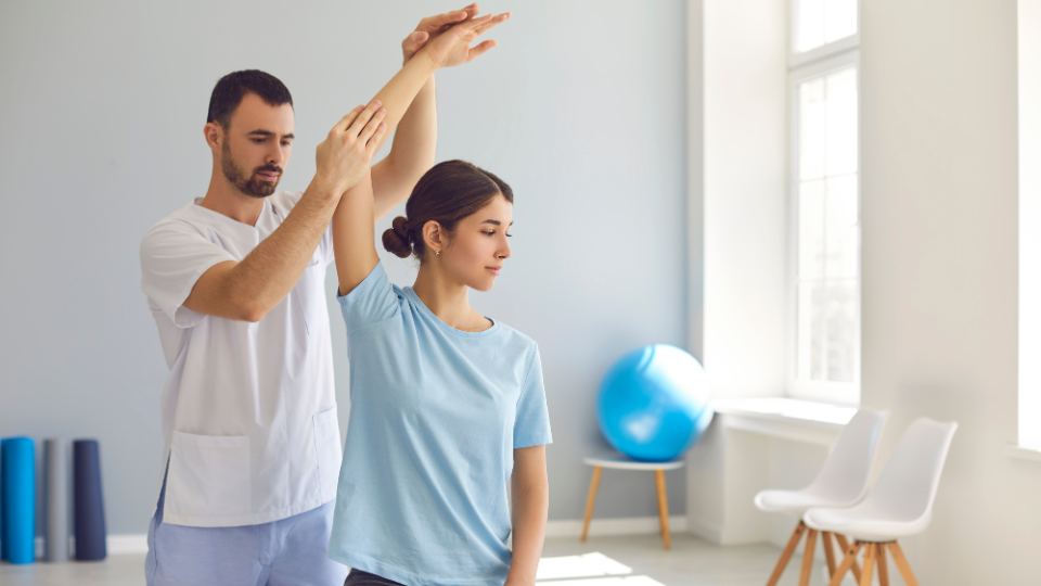 Physical therapist helping woman stretch.