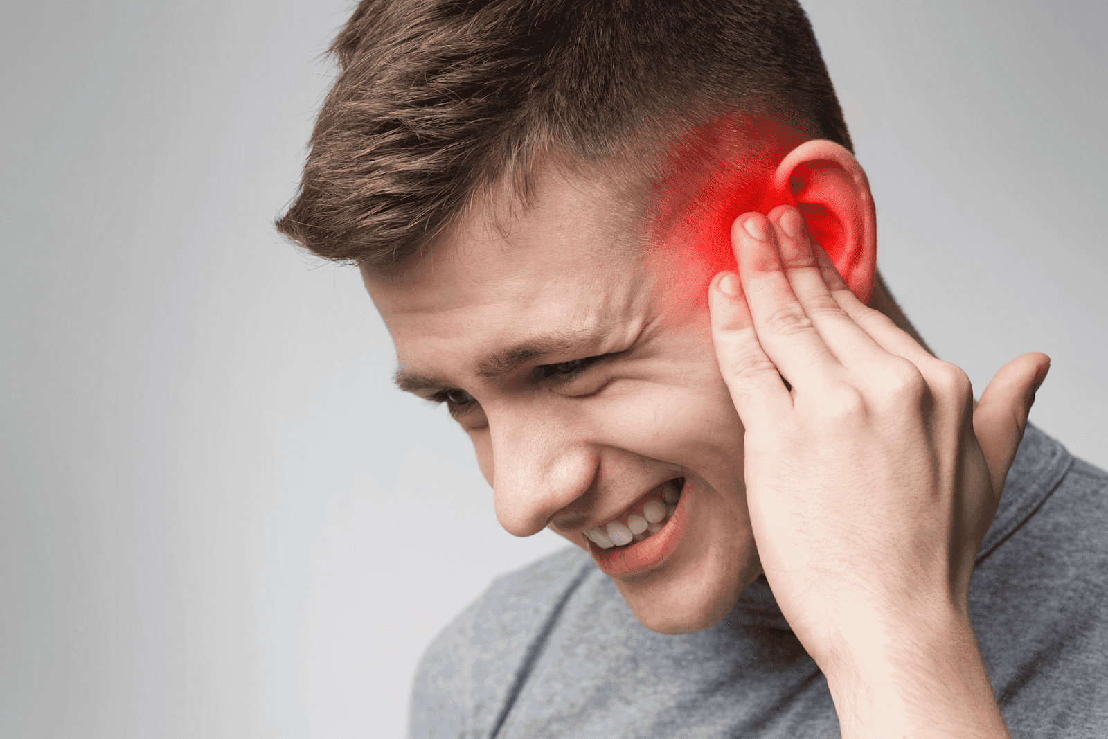 Man holding ear with red highlight showing pain.