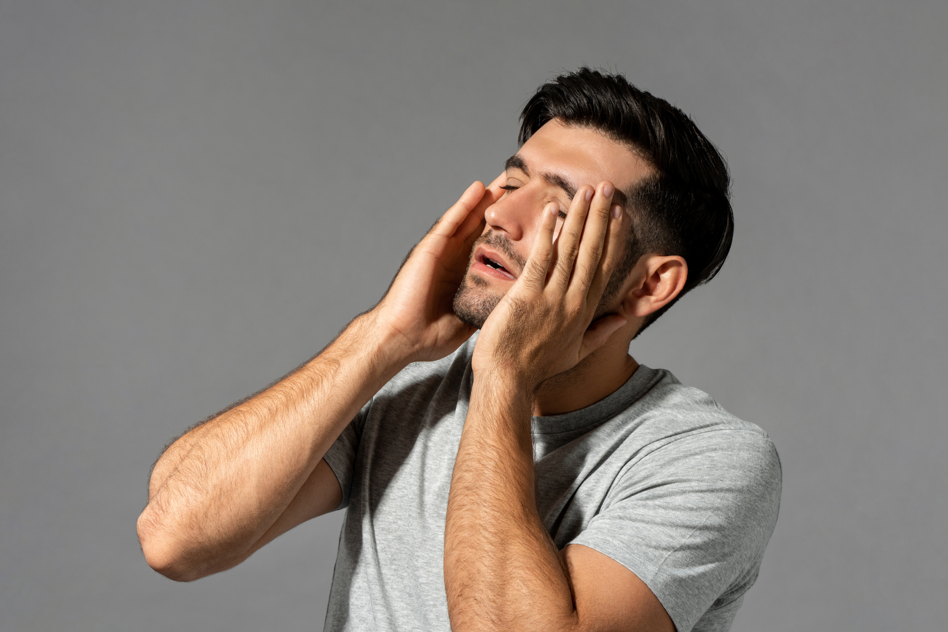 Man holding his face with both hands, appearing exhausted or stressed