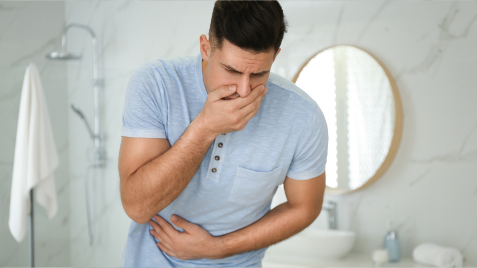 Man holding stomach with one hand and mouth with the other hand like he wants to vomit