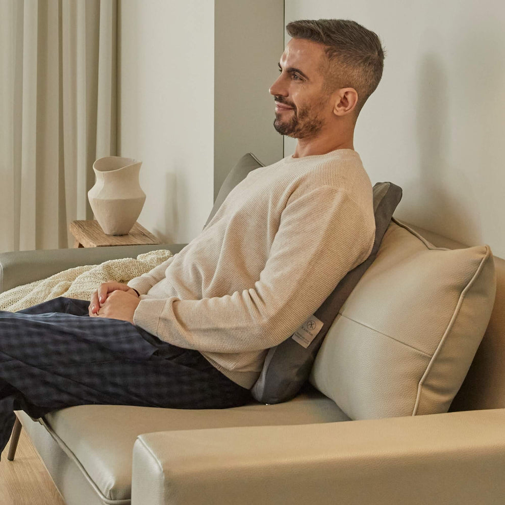 Man reclining on a couch with a back support pillow