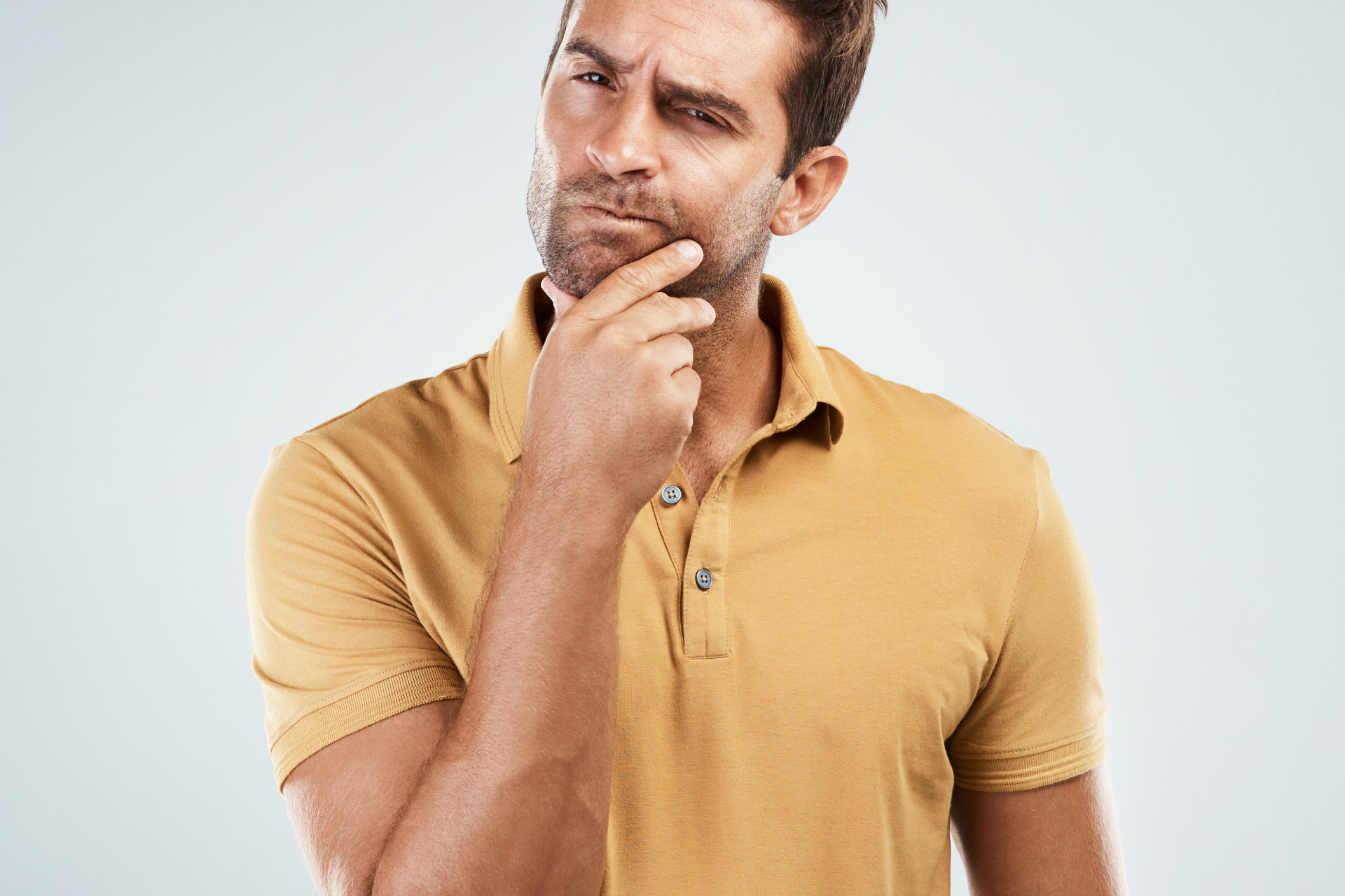 Man touching his chin with a thoughtful expression, appearing concerned or contemplative