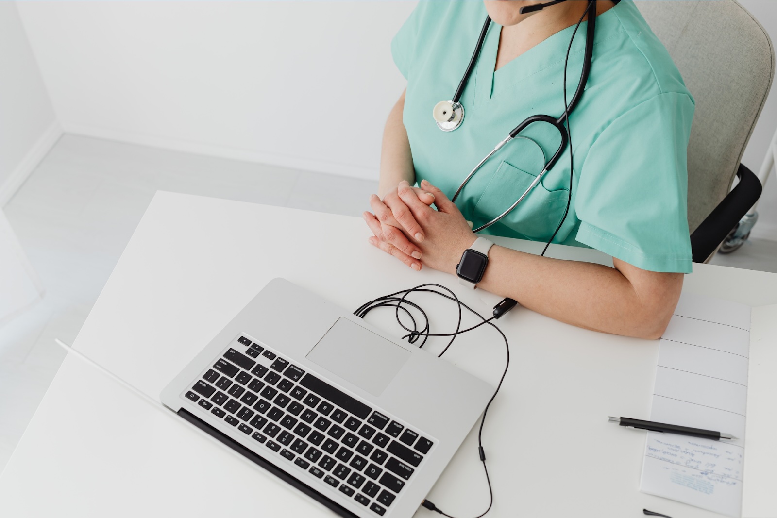 Medical professional at desk with laptop, wearing stethoscope
