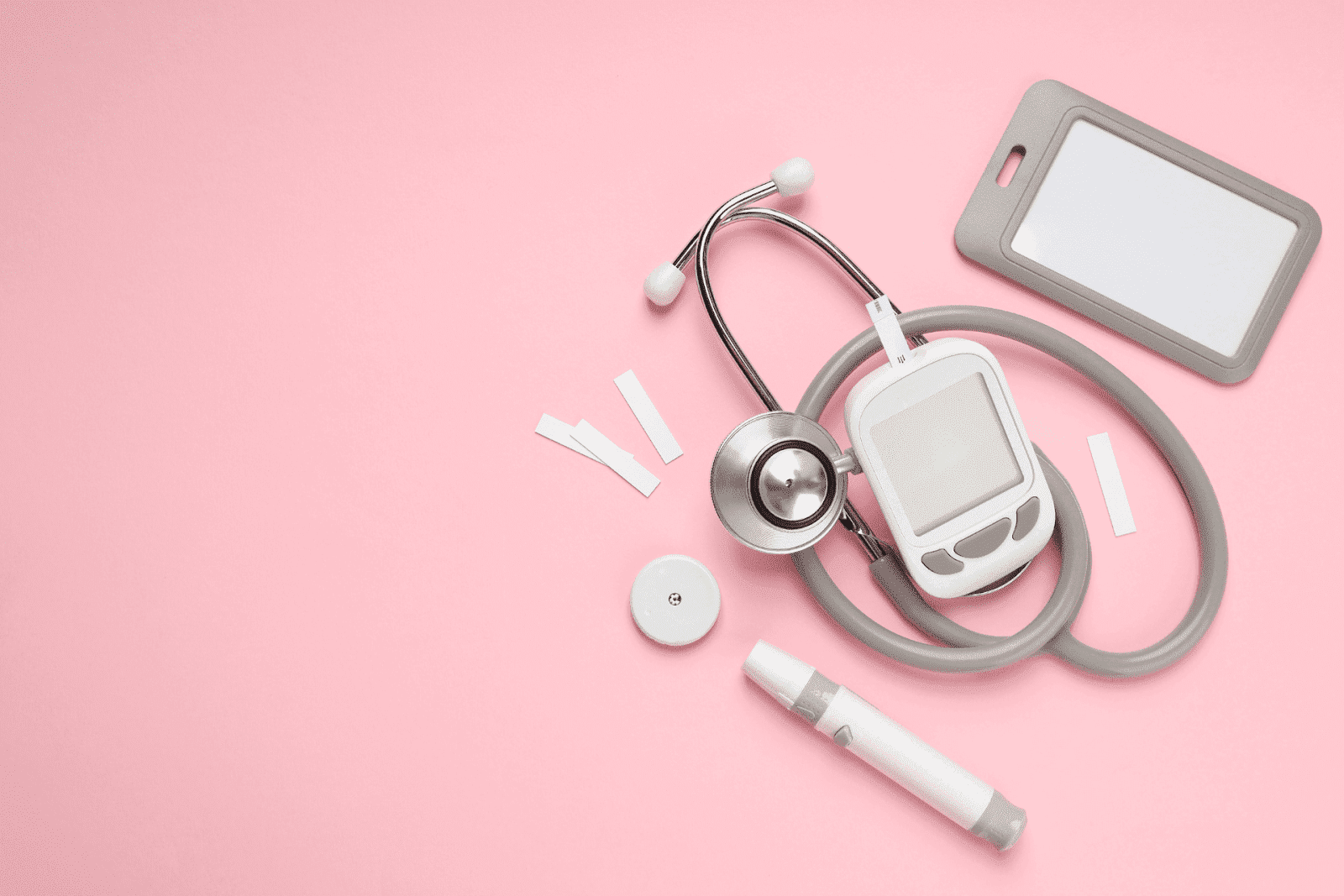 Medical tools, including a stethoscope, glucose meter, and test strips, on a pink background.