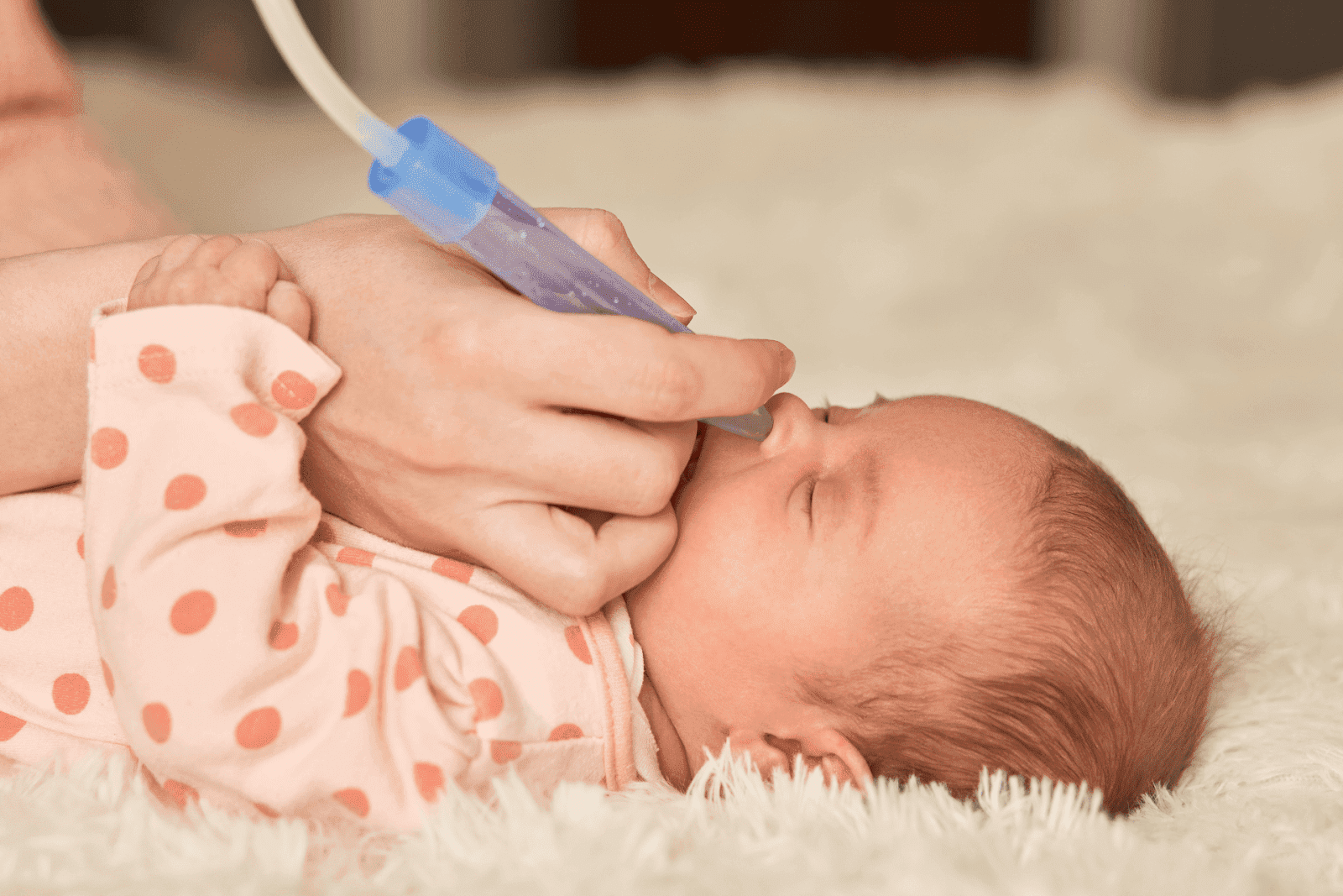 Newborn having nose suctioned with aspirator