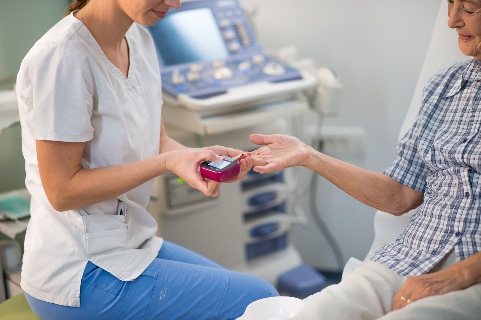 Nurse checking patient’s blood sugar with a glucose meter.