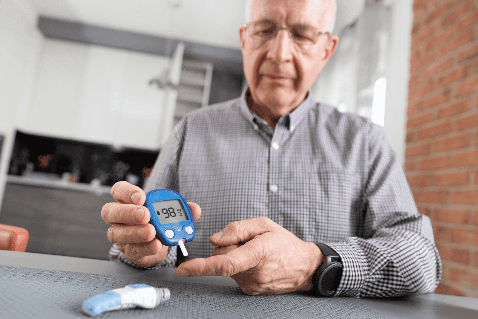 Older man checking blood sugar level with a glucose meter at home