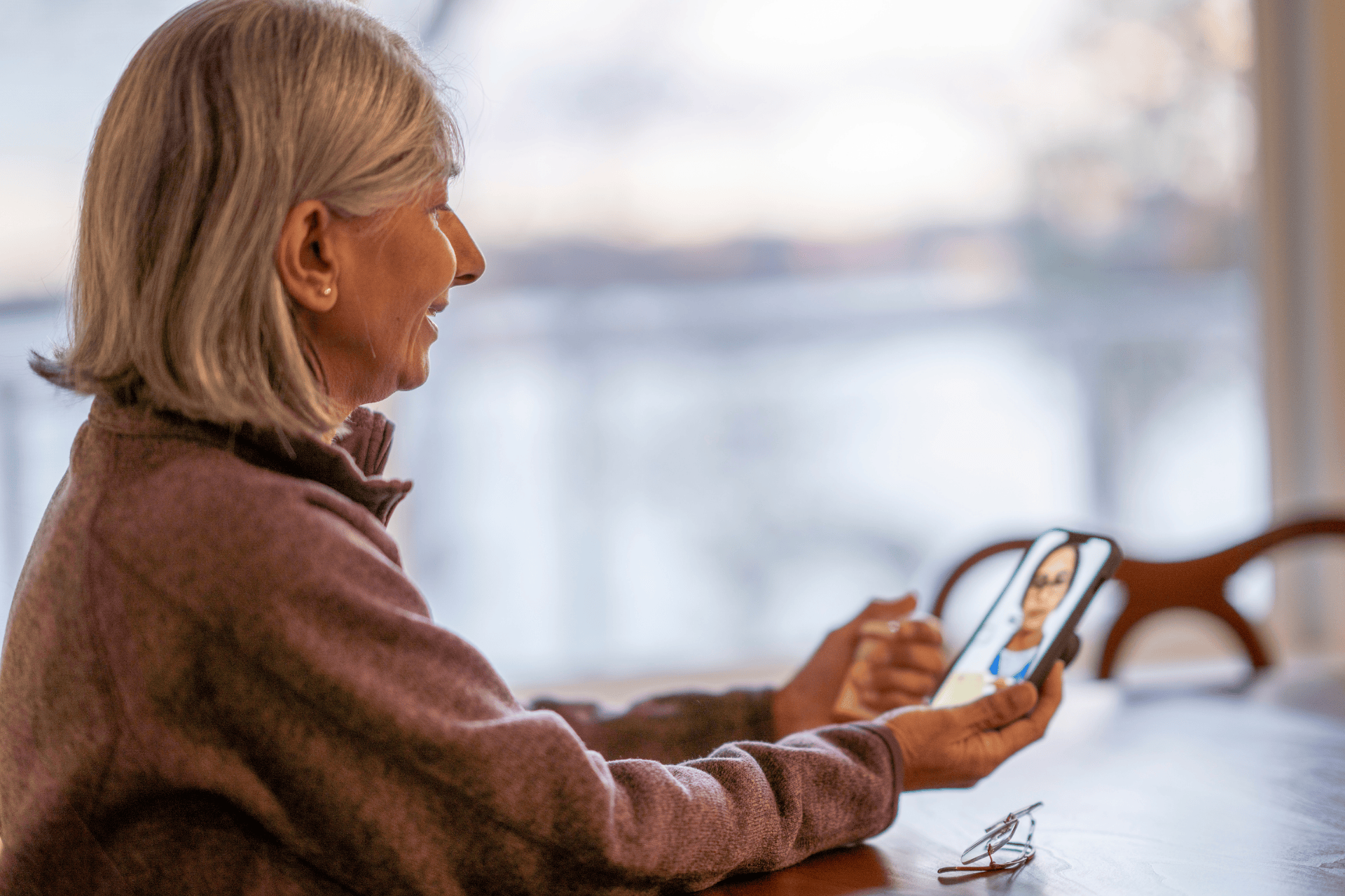 Older woman holding a smartphone and video chatting with a doctor.