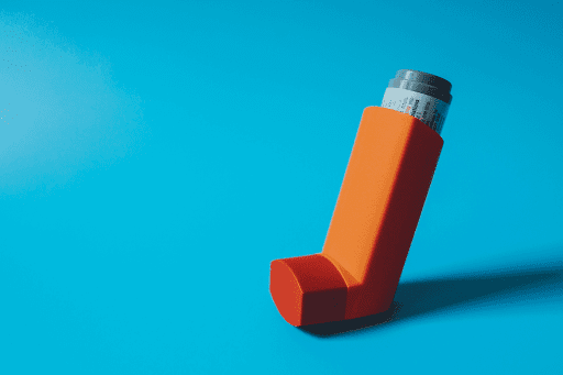 Orange asthma inhaler standing upright against a blue background