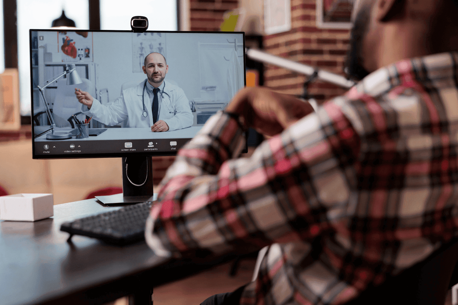 Patient having an online video consultation with a doctor on a computer screen.