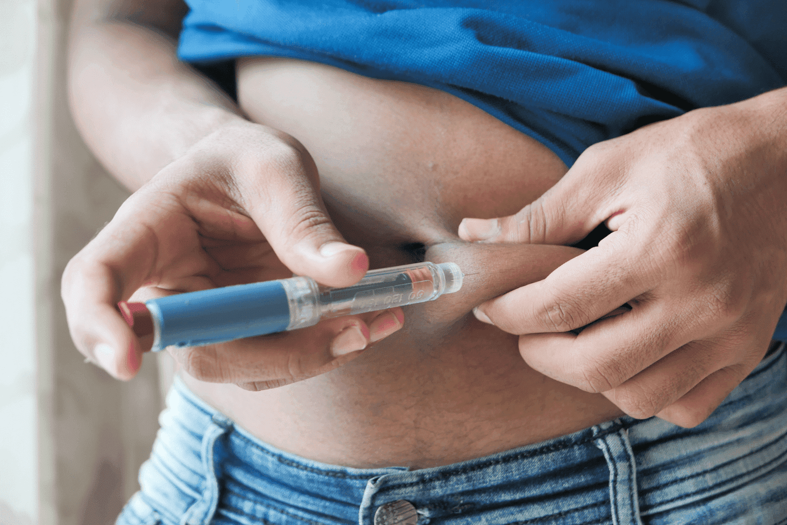 Person administering an injection into their abdomen using an insulin pen