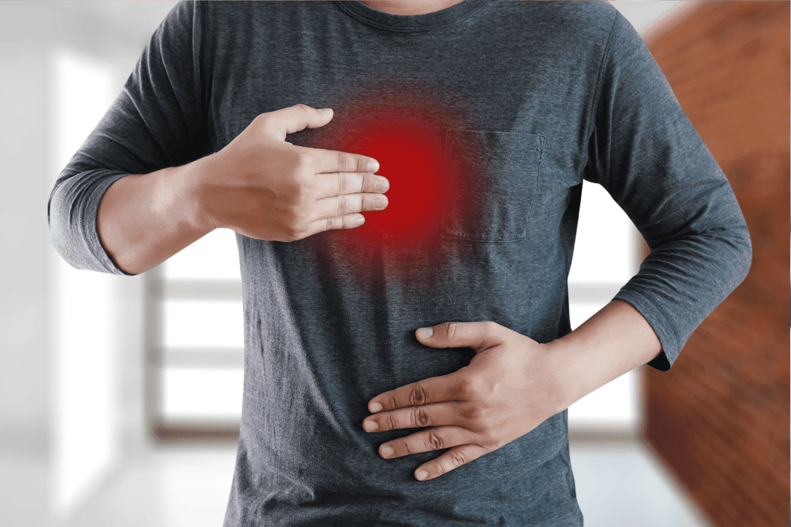 Person clutching chest and stomach with red highlight indicating pain.