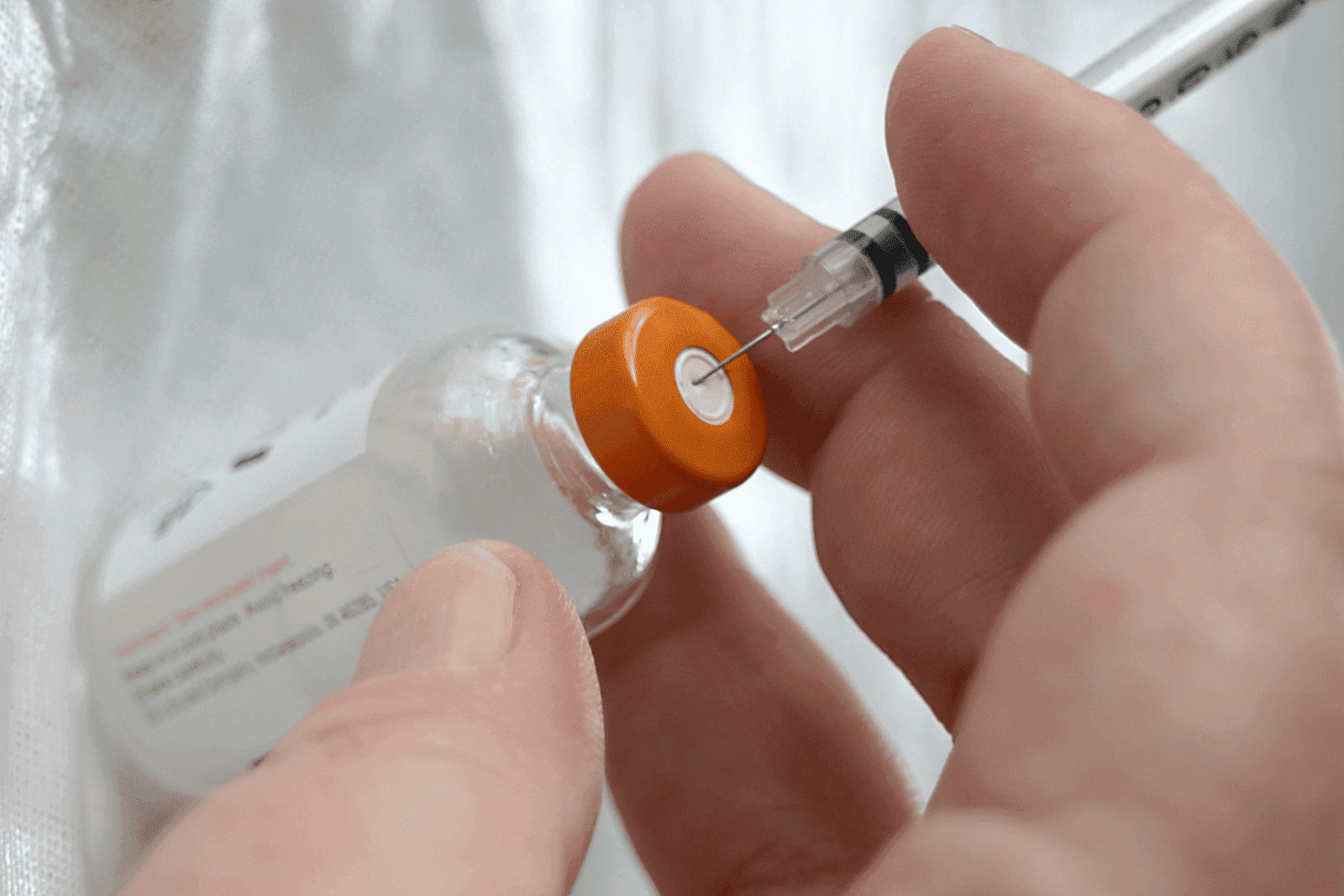 Person drawing medicine from a medical vial with a syringe