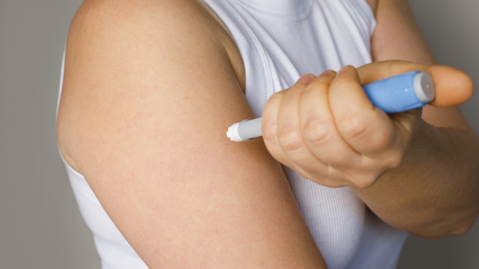 Woman giving herself a shot in the arm.