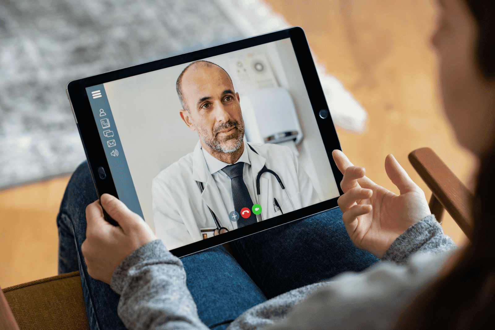 Person having an online consultation with a doctor displayed on a tablet screen.