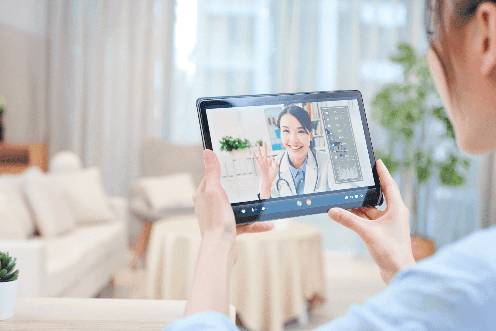 Person having an online video consultation with a smiling doctor on a tablet.Person having an online video consultation with a smiling doctor on a tablet.Person having a video call with a smiling doctor on a tablet.