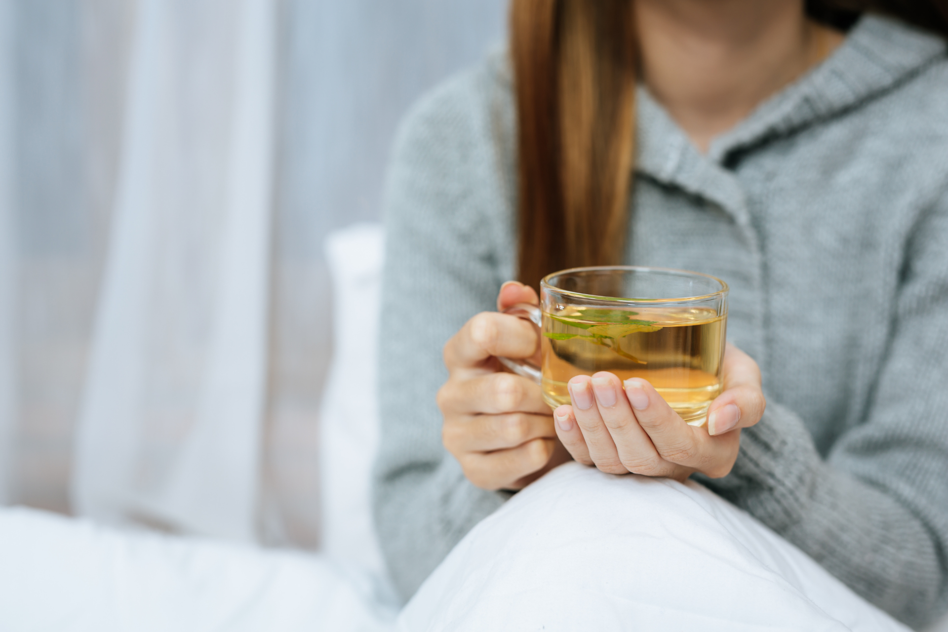 Person holding a cup of warm herbal tea with both hands