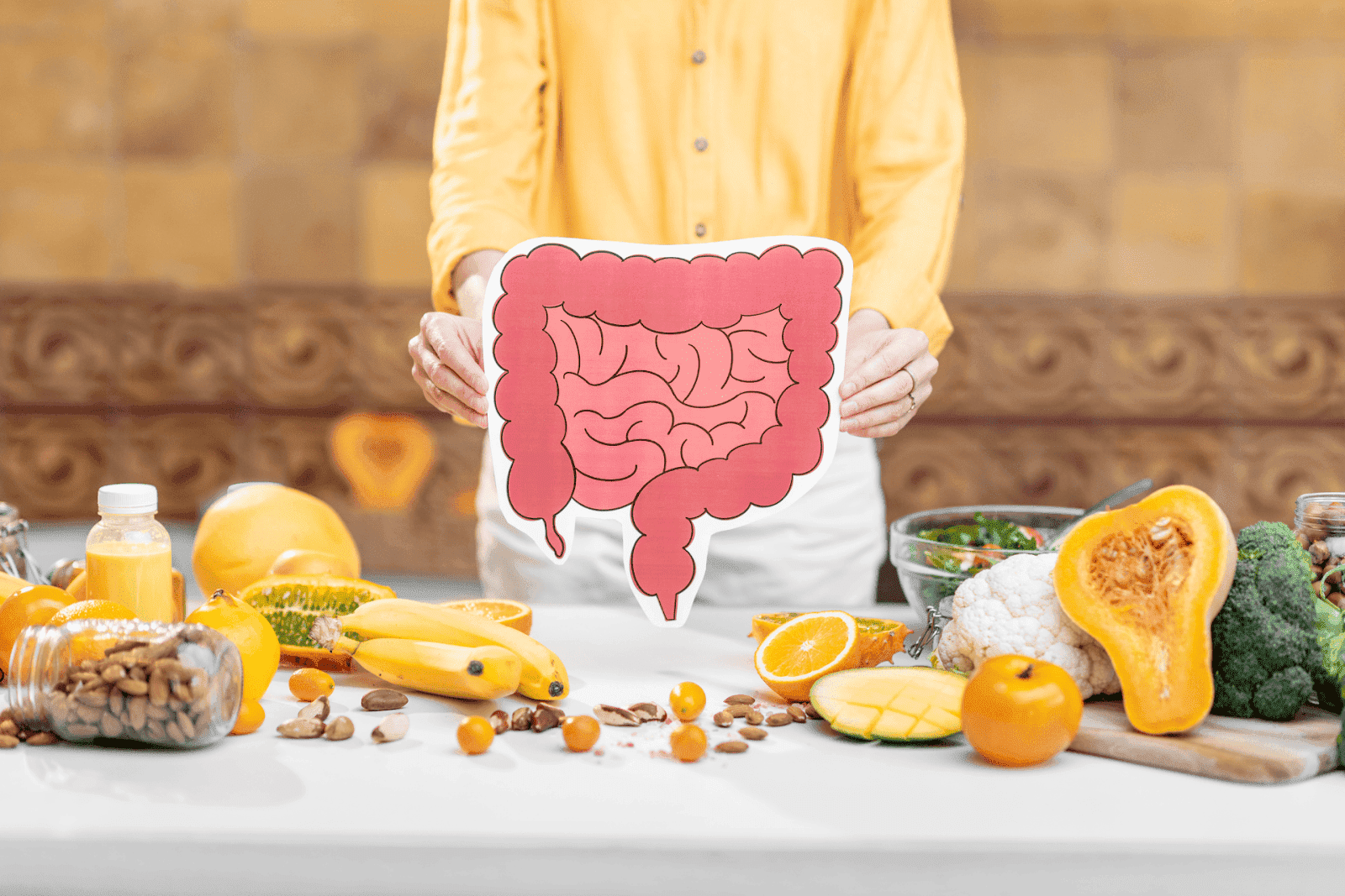 Person holding a large intestine diagram surrounded by healthy foods.