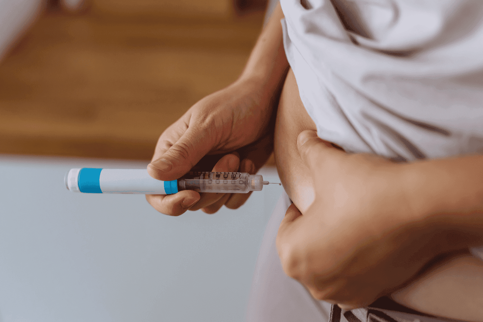 Person injecting medication into abdomen using an insulin pen