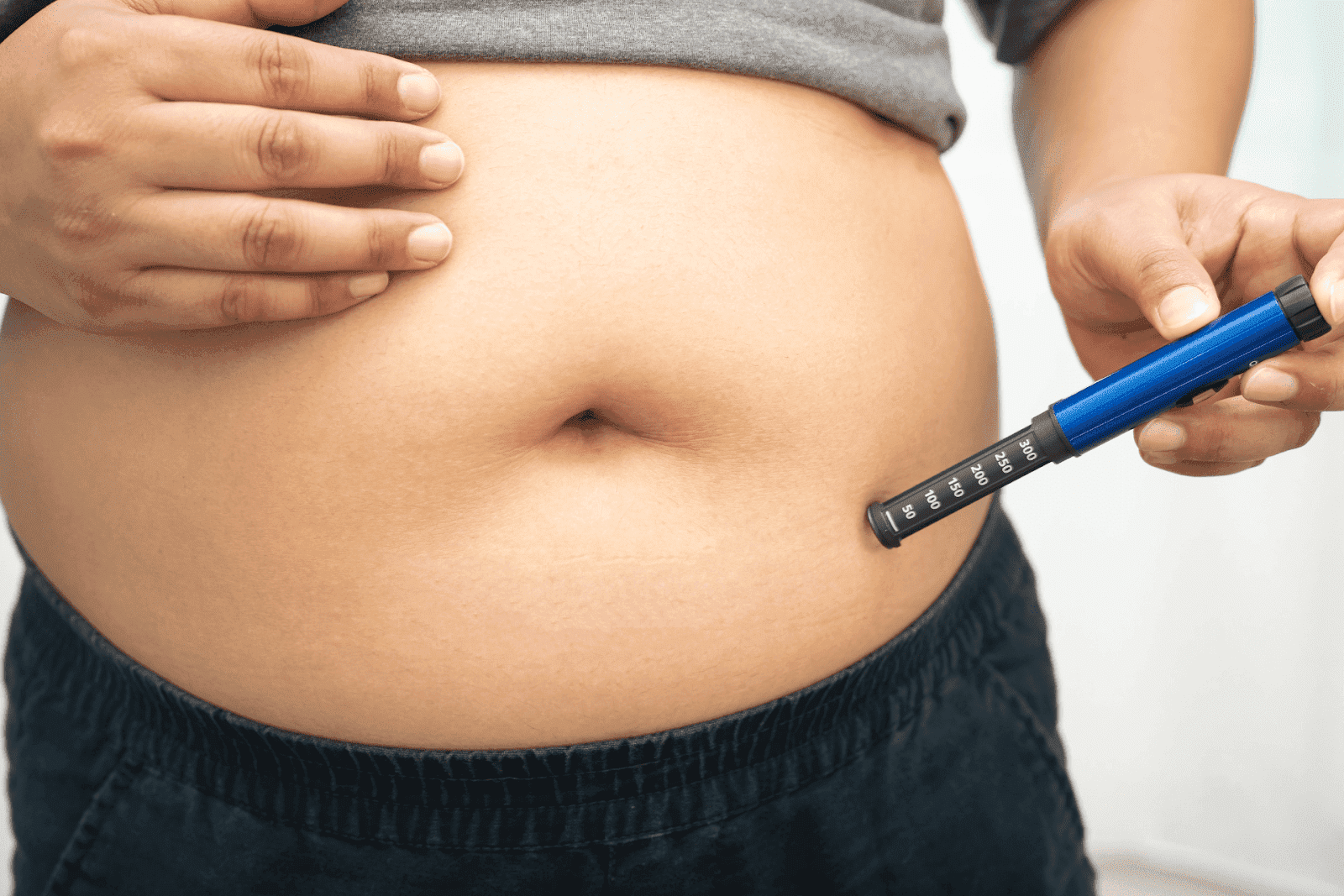 Person injecting medication into the abdomen using an insulin pen
