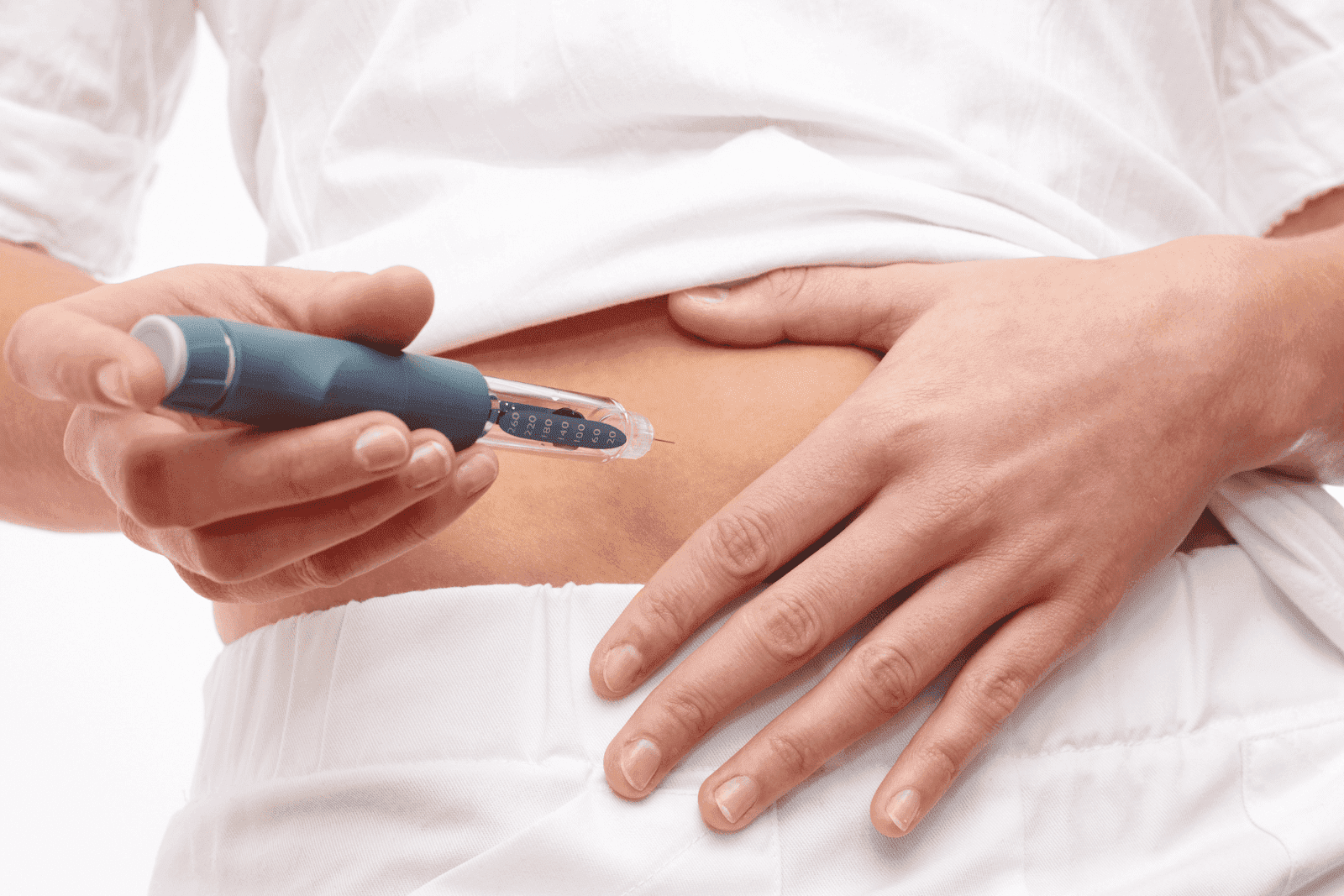 Person injecting medication into their abdomen using an injector pen