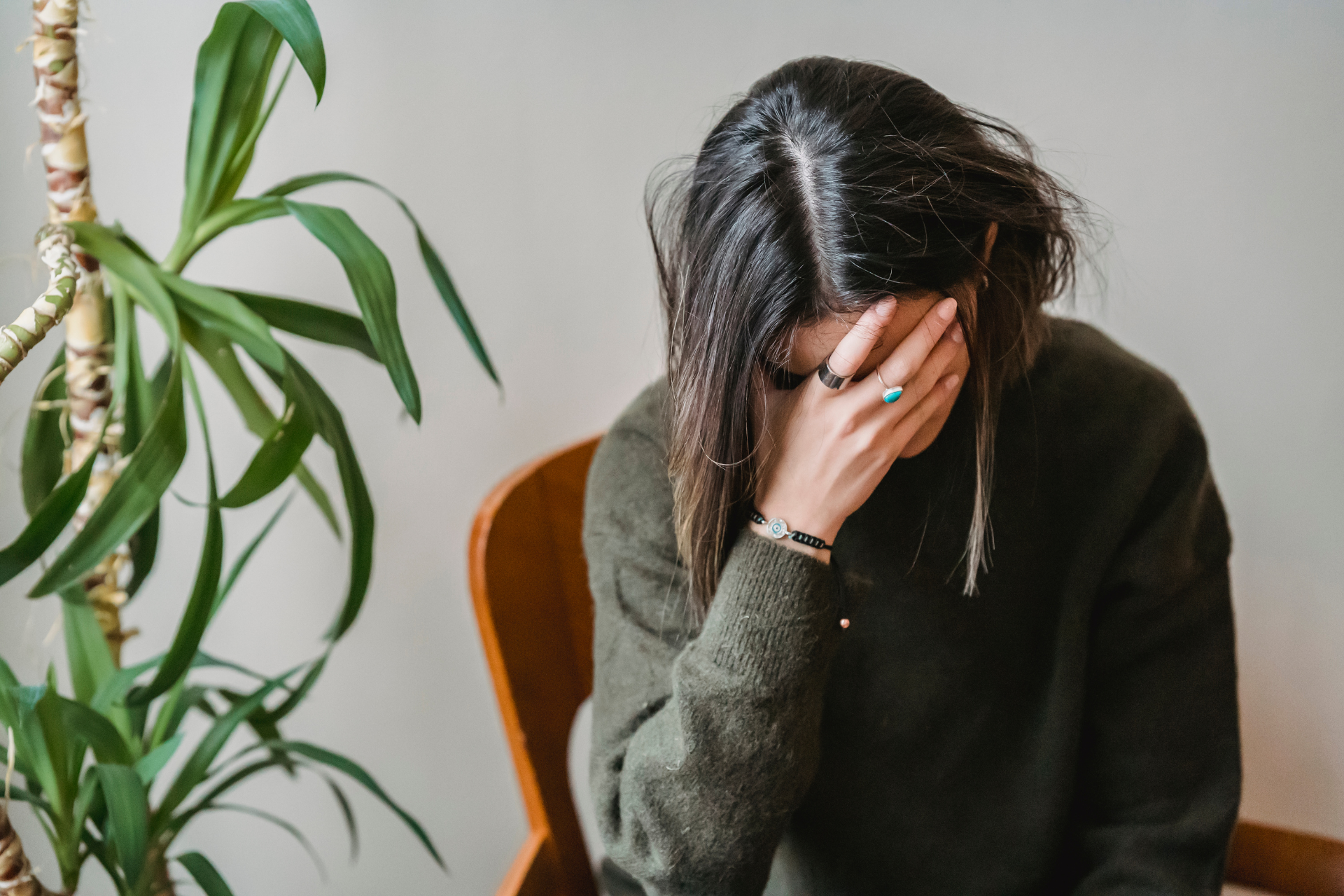 Person sitting with their head in their hand, appearing stressed or emotionally overwhelmed