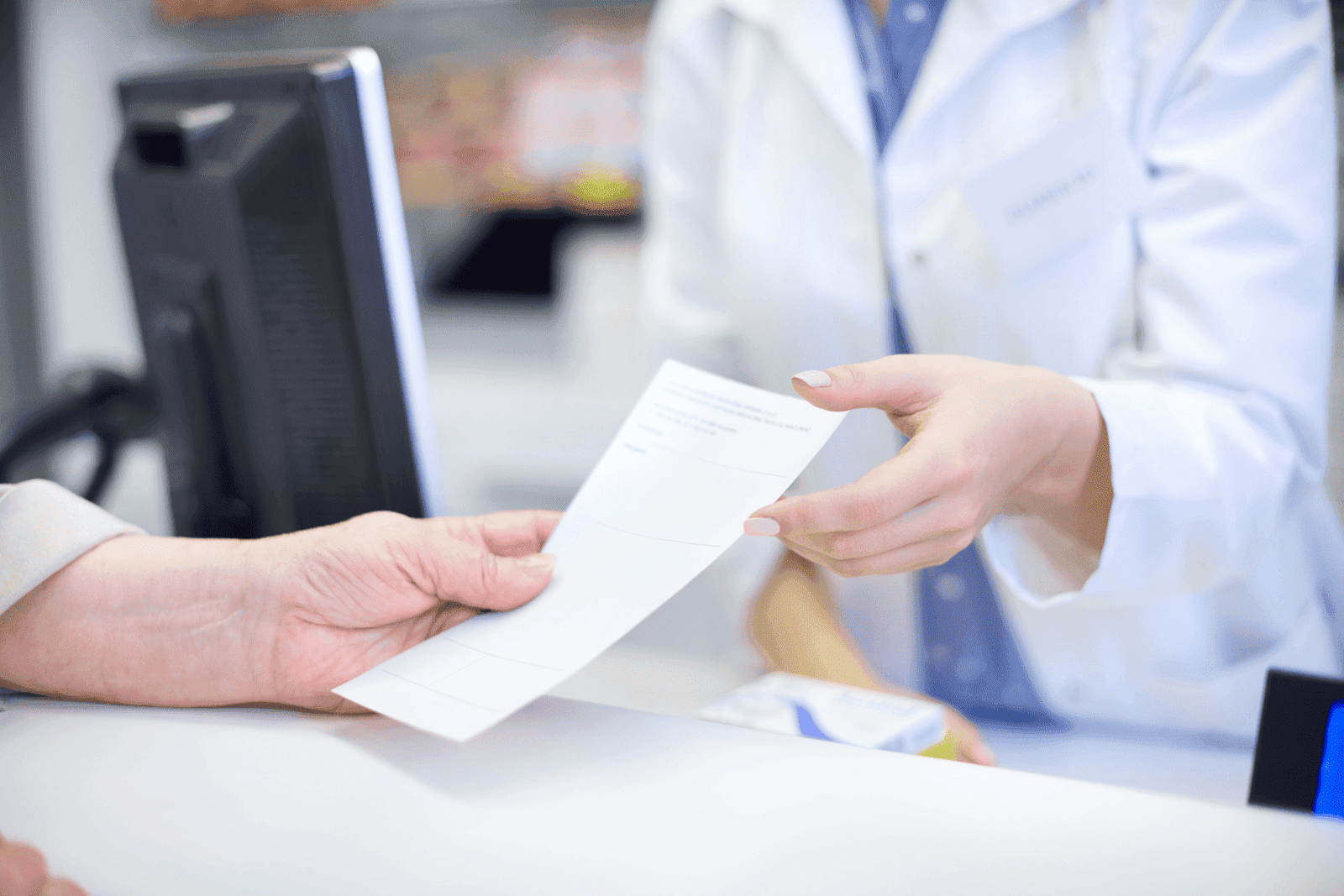 Pharmacist handing a prescription paper to a customer at the counter.