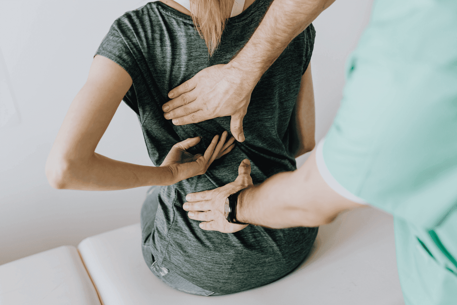Physical therapist examining a woman's lower back.