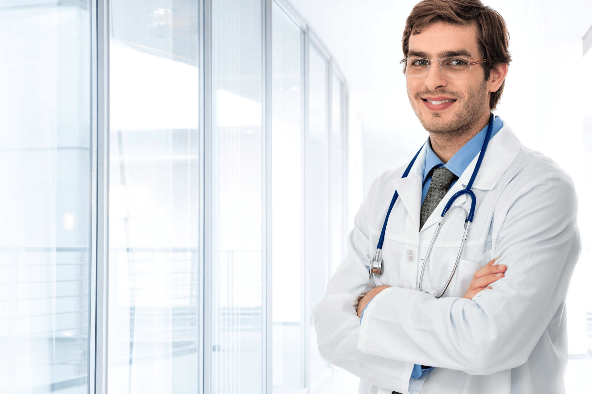 Smiling doctor with a stethoscope standing in a bright medical office.