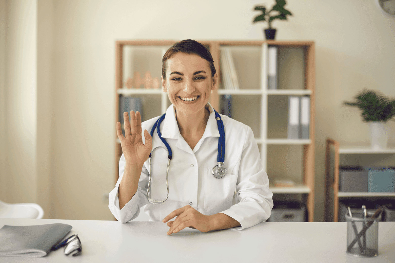 Smiling doctor waving during an online consultation.
