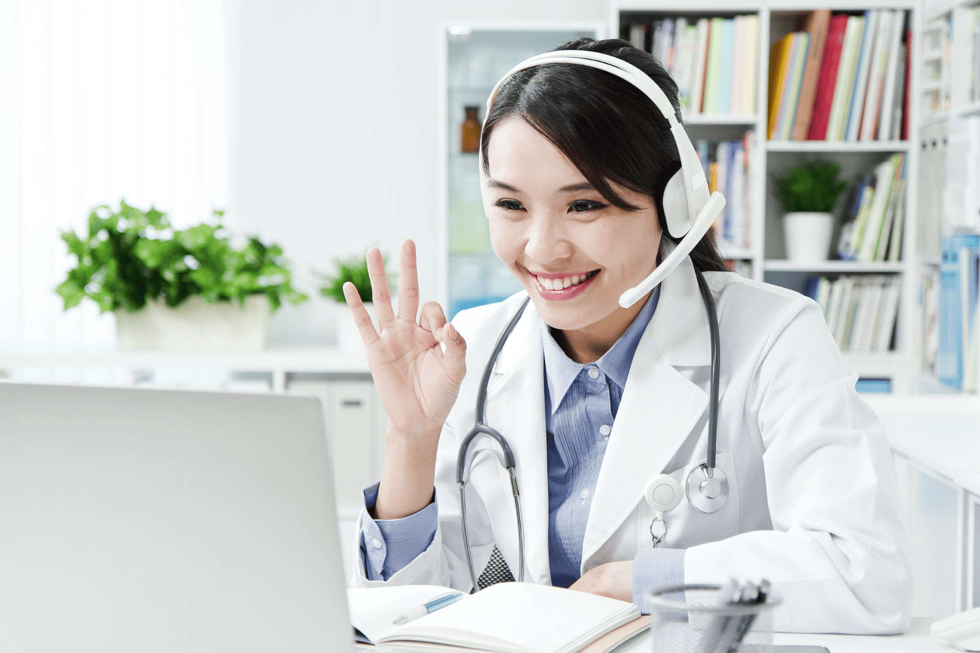 Smiling female doctor wearing a headset during an online consultation.