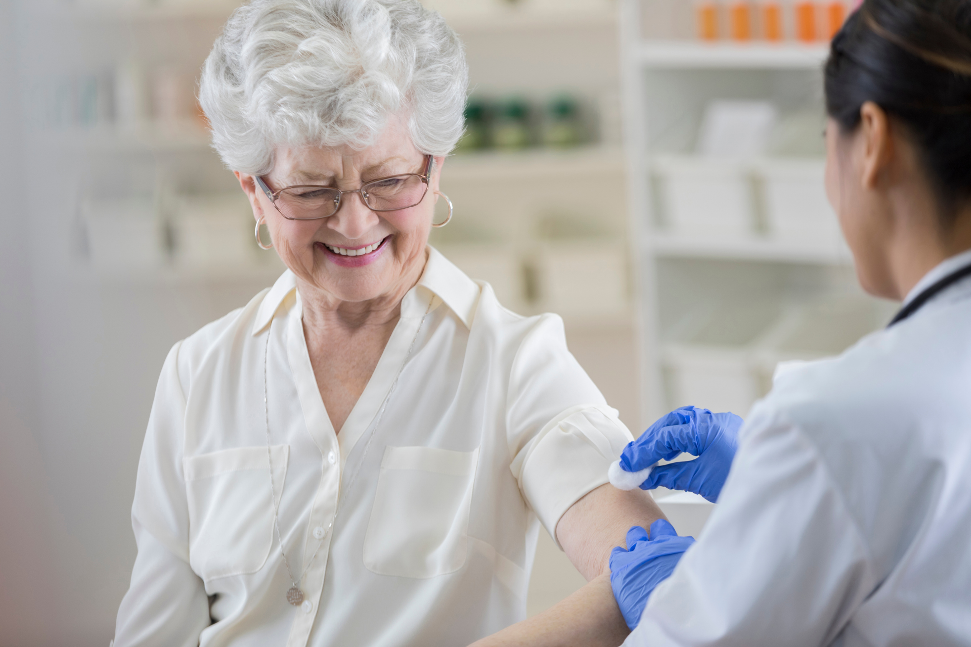Smiling older woman receiving a flu shot from a healthcare professional